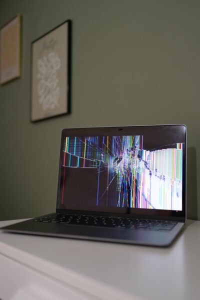 Laptop abierta sobre una mesa con la pantalla rota y distorsionada, como metáfora de los límites de la inteligencia artificial en la producción de contenidos.